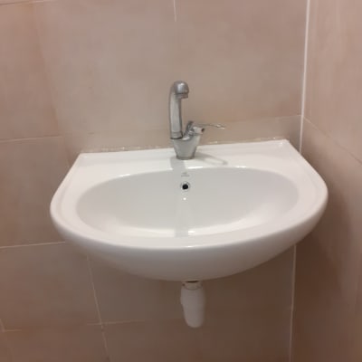 כיור לבן עם ברז מתכת וקיר קרמיקה