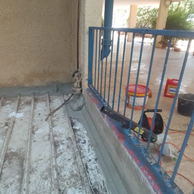 חומרי איטום וכלים על רצפה ליד מעקה