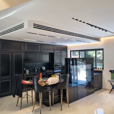 מטבח מודרני עם ארונות שחורים וכיסאות בר גבוהים