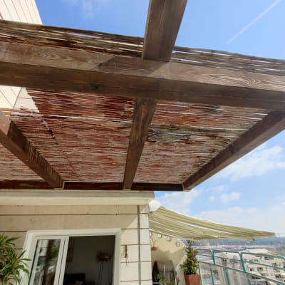 פרגולה מעץ עם כיסוי קנים בגינה