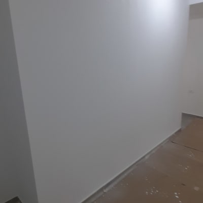 קיר צבוע בלבן עם דלי צבע על הרצפה