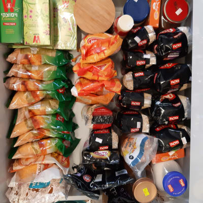 מגוון מוצרים מאורגנים במגירה, כולל תבלינים וקטניות.