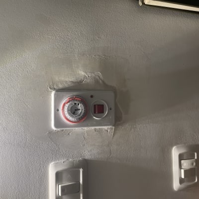 שעון טיימר חשמלי על קיר עם מתגי תאורה