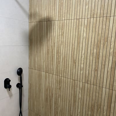 מקלחת עם ראש גשם שחור וקיר אריחים מעץ