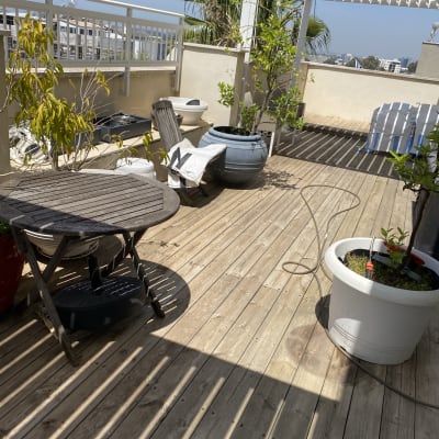 מרפסת עץ עם עציצים וצינור השקיה