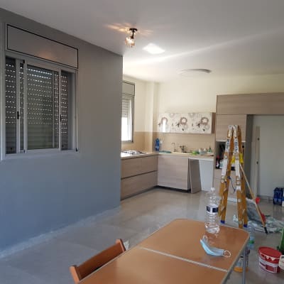 סולם, דלי צבע ומברשות בחדר צבוע חלקית