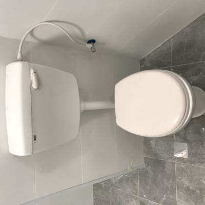 אסלה ומיכל הדחה מותקנים על רצפת אריחים אפורה