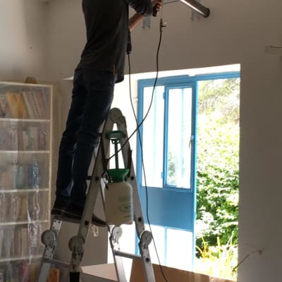 אדם מתקין מזגן על קיר בעזרת מקדחה