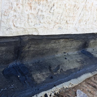 איטום קיר חיצוני עם חומר שחור על בטון