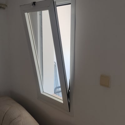 חלון אלומיניום פתוח חלקית על קיר לבן