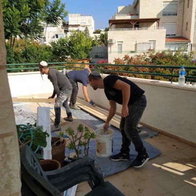 הצוות צובע בצבע של הפרגולה,ומכין את מרישי העץ להתקנה .