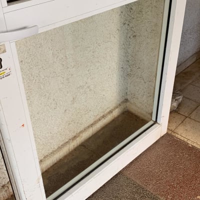 דלת זכוכית עם מסגרת לבנה על רצפה מרוצפת