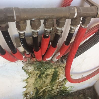 צינורות מים עם חיבורים על קיר רטוב