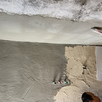 קיר בטון עם אריחים בתהליך הדבקה ושכבת טיח