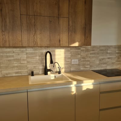 מטבח משופץ עם כיור וברז מודרניים, ארונות עץ וקיר אריחים