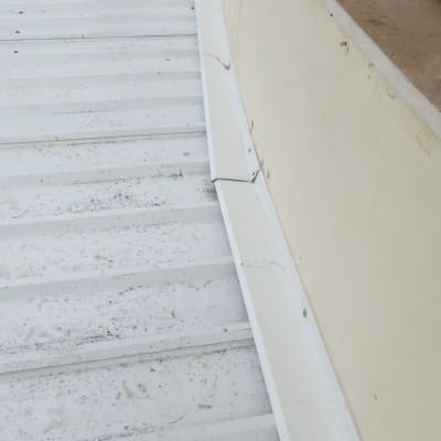 גג מתכת לבן עם סימני לכלוך ורגלי אדם