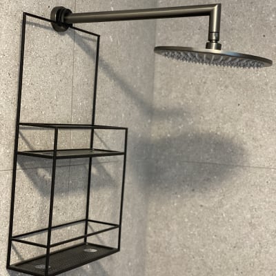 ראש מקלחת מתכתי עם מדף שחור על קיר אפור