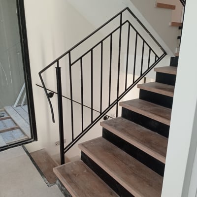 מעקה מתכת שחור על מדרגות עץ