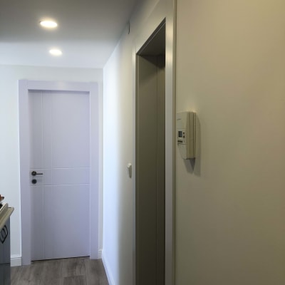 מסדרון עם דלת לבנה, רצפת עץ ותאורה שקועה