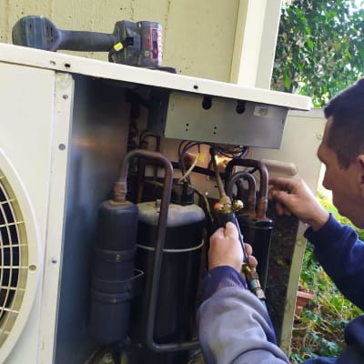 טכנאי עובד על מערכת מיזוג אוויר חיצונית