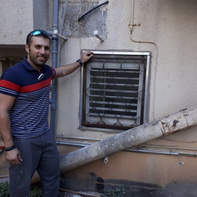 אדם ליד חלון עם מסגרת אלומיניום על קיר חיצוני