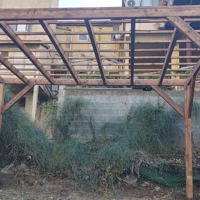 פרגולה מעץ בגינה עם קורות עץ חומות