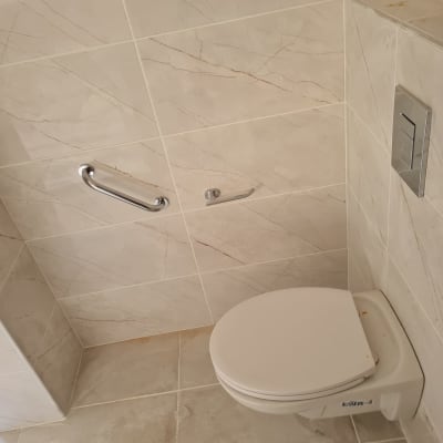 שירותים עם אריחים חדשים ומאחז יד מתכת