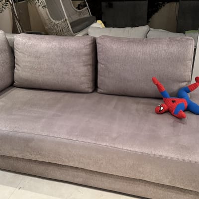 ספה אפורה עם בובה וכלב ליד חלון