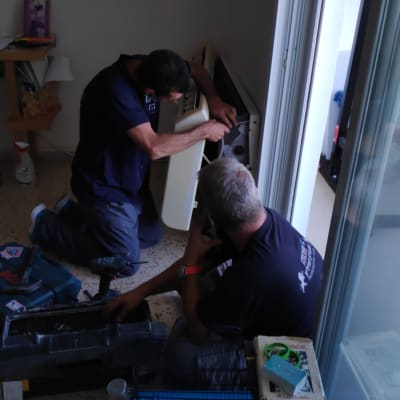 שני אנשים מתקנים מזגן עם כלים על הרצפה