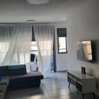 סלון עם ספה, טלוויזיה תלויה, וילון לבן