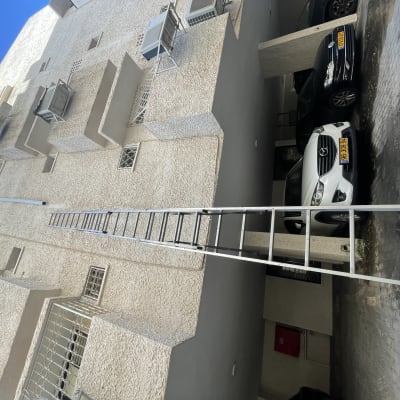 סולם מתכת נשען על קיר בניין