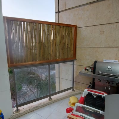 גדר במבוק על מרפסת עם גריל גז וכריות