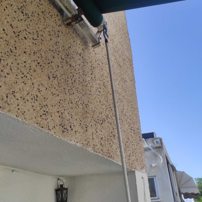 סוכך ירוק מחובר לקיר עם מוט מתכת