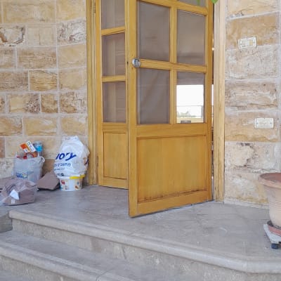 שקיות עם חומרים וכלים לשיפוץ ליד דלת עץ פתוחה