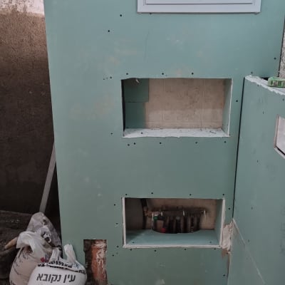 קיר גבס עם פתחים לצנרת ושקיות פסולת בנייה