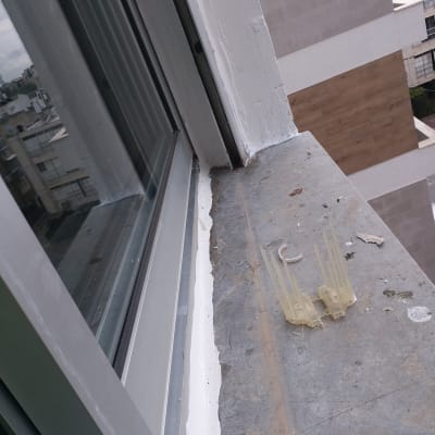 איטום חלון עם חומר לבן על אדן בטון