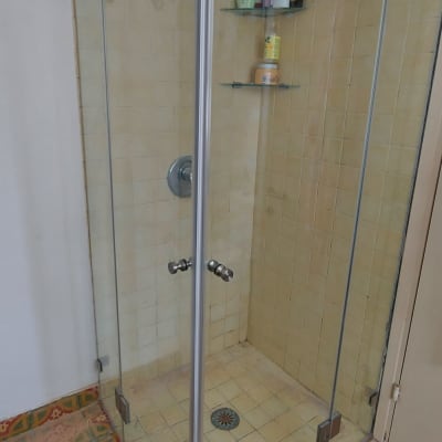 מקלחון זכוכית עם מדף ומוצרי רחצה