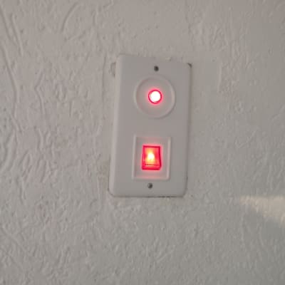 מתג עם נורית חיווי אדומה על קיר