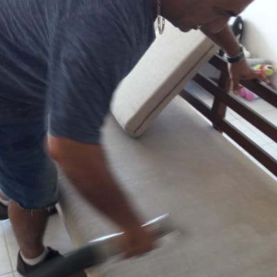 אדם מנקה ספה עם שואב אבק