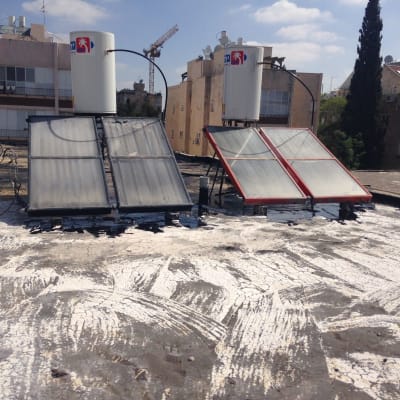 גג עם קולטי שמש ואיטום לבן סביבם