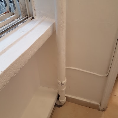 צינור וקיר צבועים בלבן ליד חלון