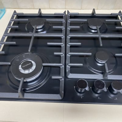 כיריים גז שחורות עם ארבעה מבערים וכפתורי שליטה