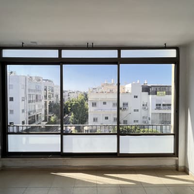 חלון גדול עם תריסים פתוחים ונוף עירוני