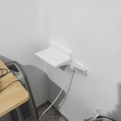 מדף לבן מותקן על קיר עם שקע חשמל