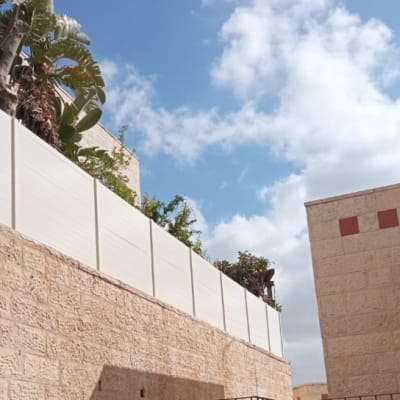 גדר אלומיניום לבנה על קיר אבן