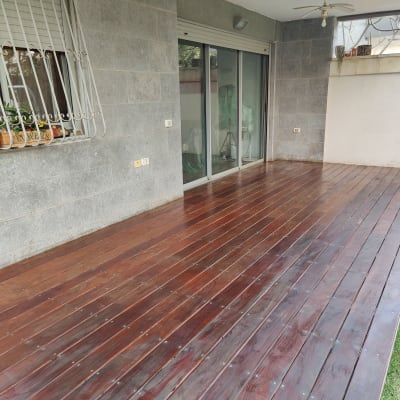 דק עץ כהה ליד קיר אבן וחלון עם עציצים