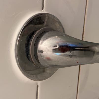 ידית ברז מתכתית על קיר אריחים לבנים