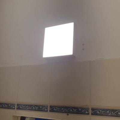 מנורת קיר מרובעת מוארת על קיר לבן