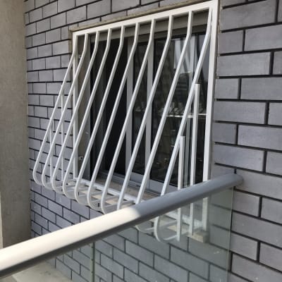 סורגי מתכת לבנים על חלון קיר לבנים אפור