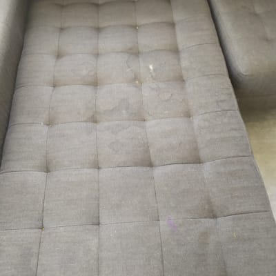 ספה אפורה עם כתמים ולכלוך על המושב